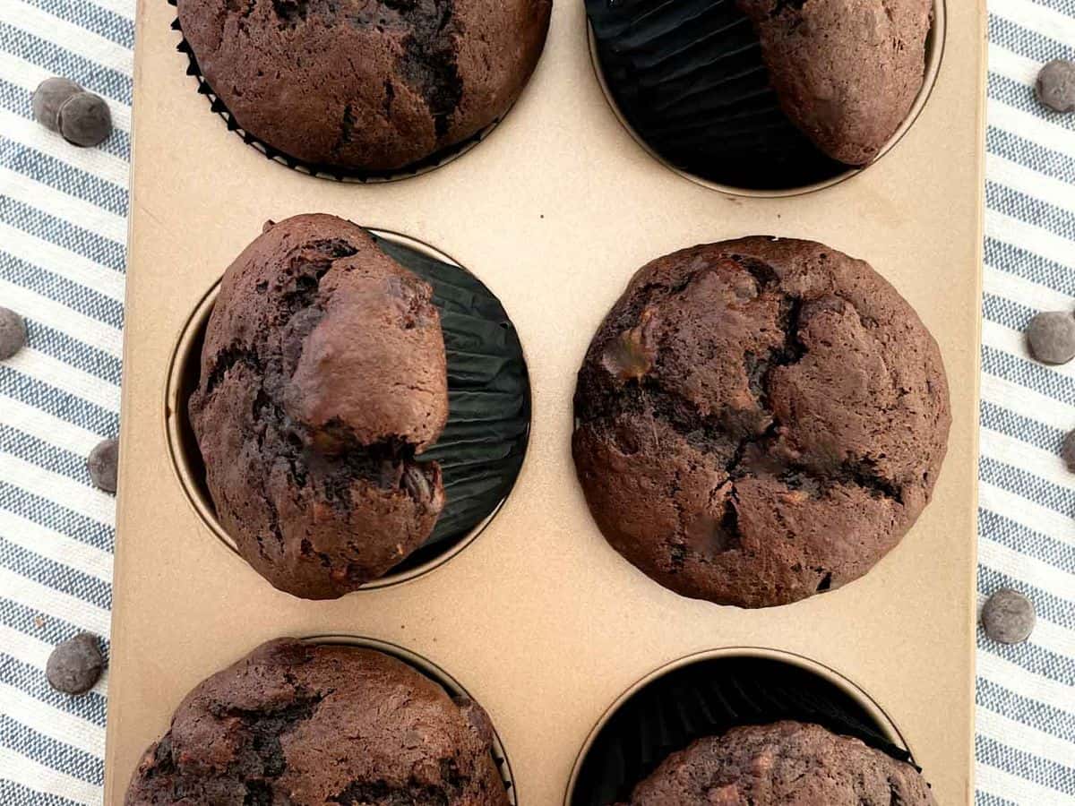 six of the best chocolate chocolate chip banana muffins inside a gold muffin tin