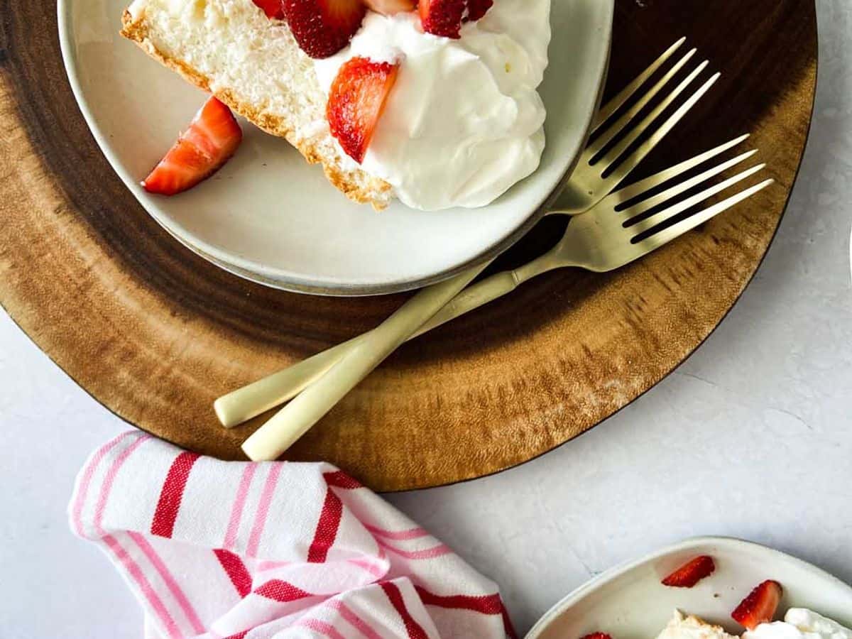 angel food cake on a plate topped with whipped cream and strawberries