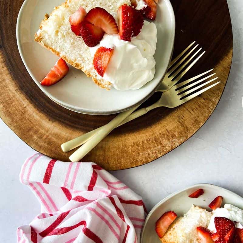 angel food cake on a plate topped with whipped cream and strawberries