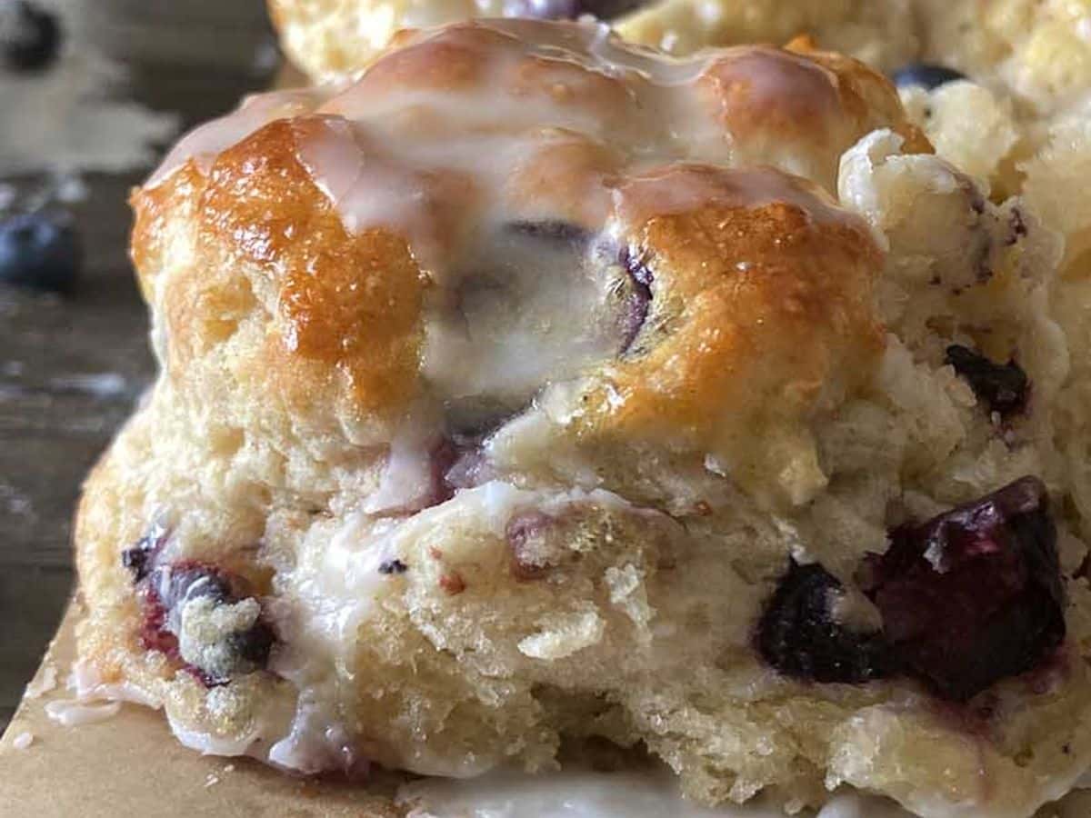 boberry biscuits with blueberries and icing from the side on the back of a baking sheet