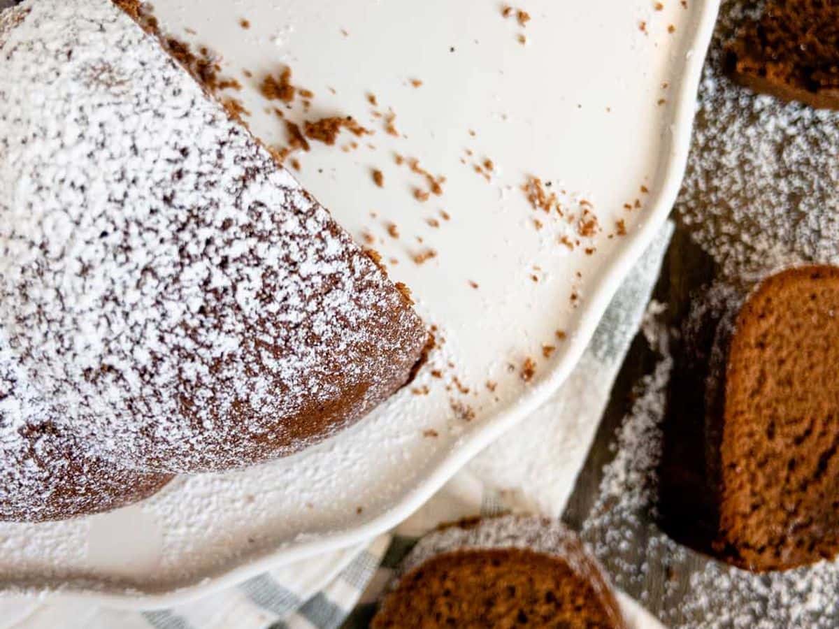 chocolate pound cake covered with powdered sugar with some slices cut out