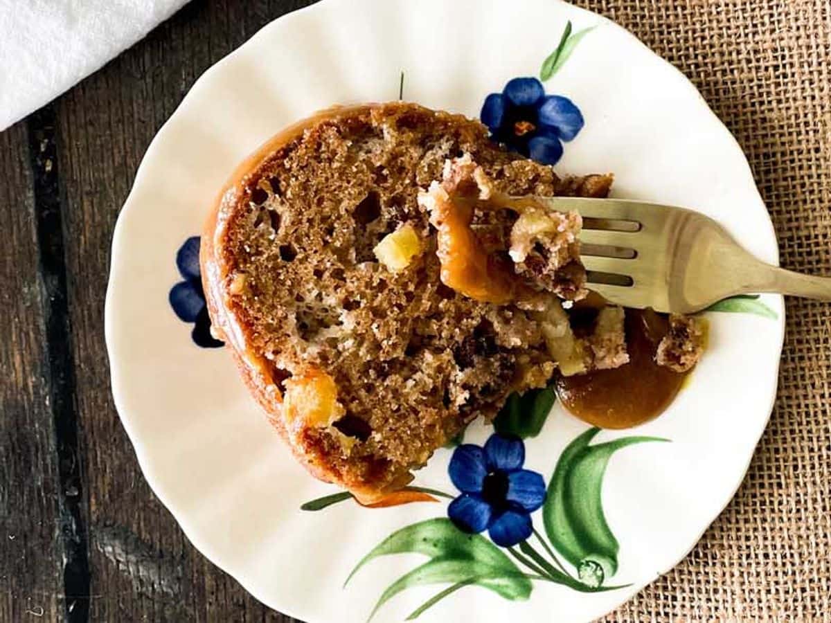 slice of cinnamon apple cake on a plate with a bite on a fork