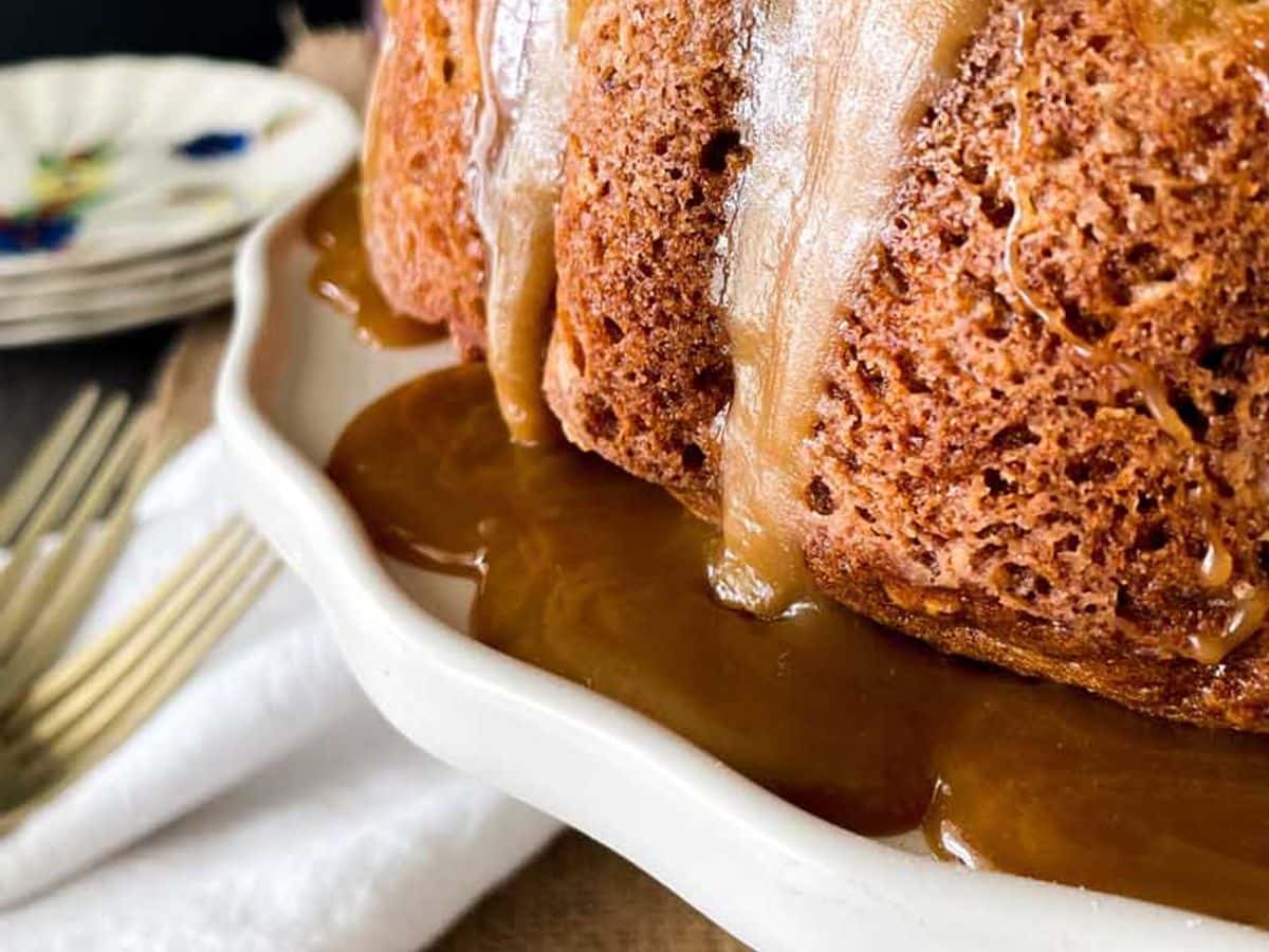 side view of cinammon apple cake on cake stand with caramel glaze
