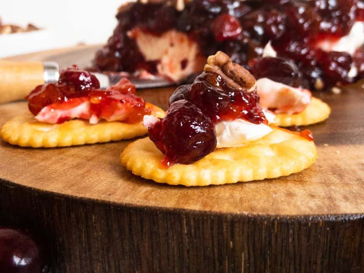 cranberry cream cheese dip closeup on a cracker with the rest of the block of dip in the background