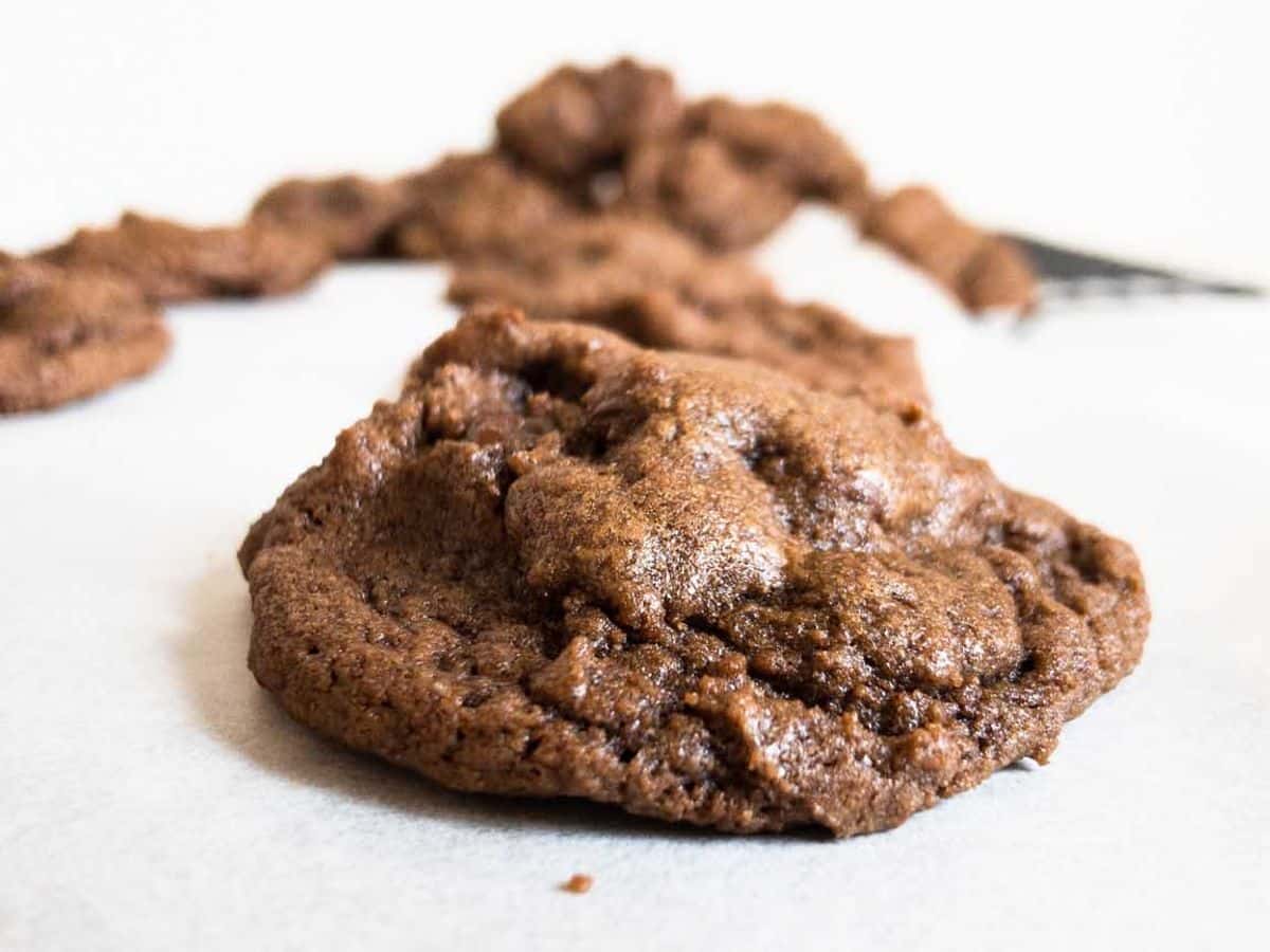 double chocolate chip cookies on back of sheet pan with single cookie in focus and other cookies blurred in background
