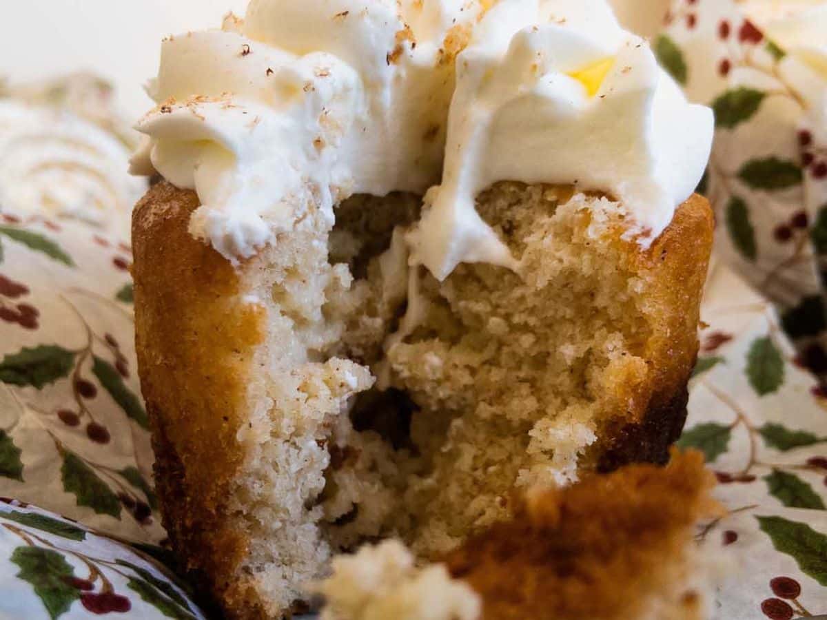 egg nog (tres leches) cupcakes topped with mascarpone and grated nutmeg, with bite on fork showing the inside of the cupcake