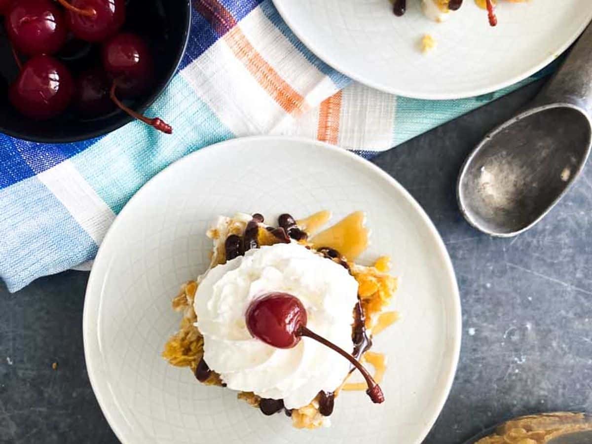 plates of fried ice cream with whipped cream and cherry with bowl of cherries on the side