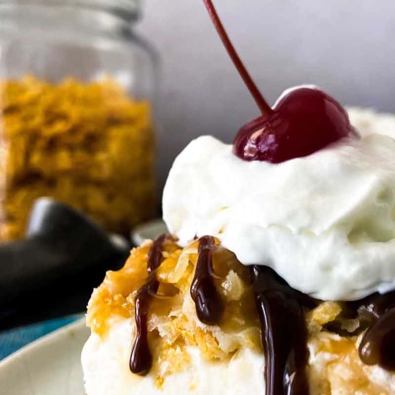 close up of fried ice cream on a plate with chocolate syrup, whipped cream, and a cherry on top