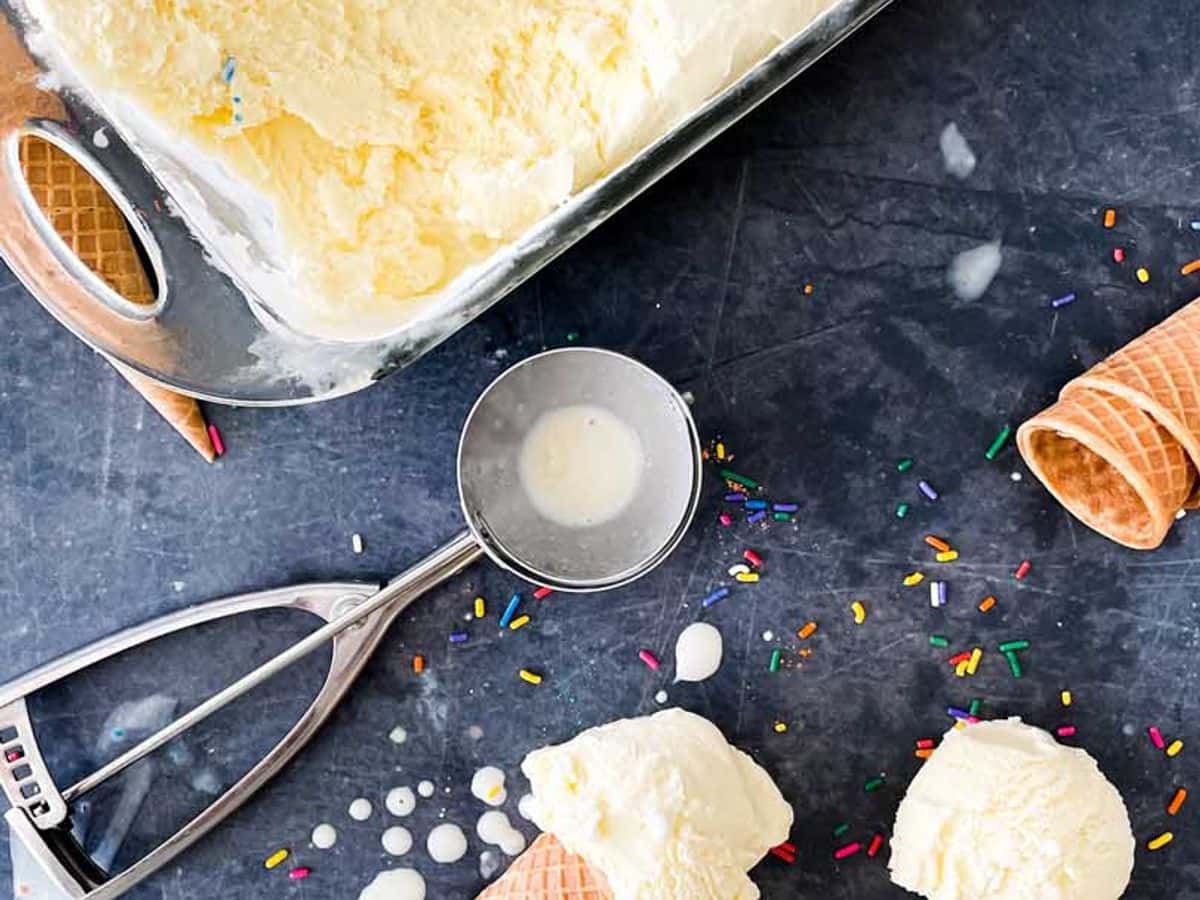container of homemade custard with three scooped ice cream cones beside it