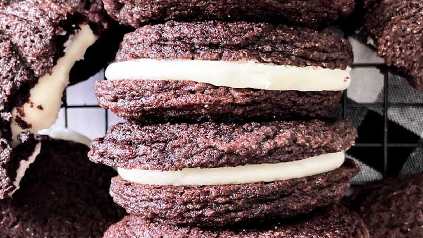 homemade oreo cookies with mascarpone filling lined up next to each other on a cooling rack surrounded by other cookies