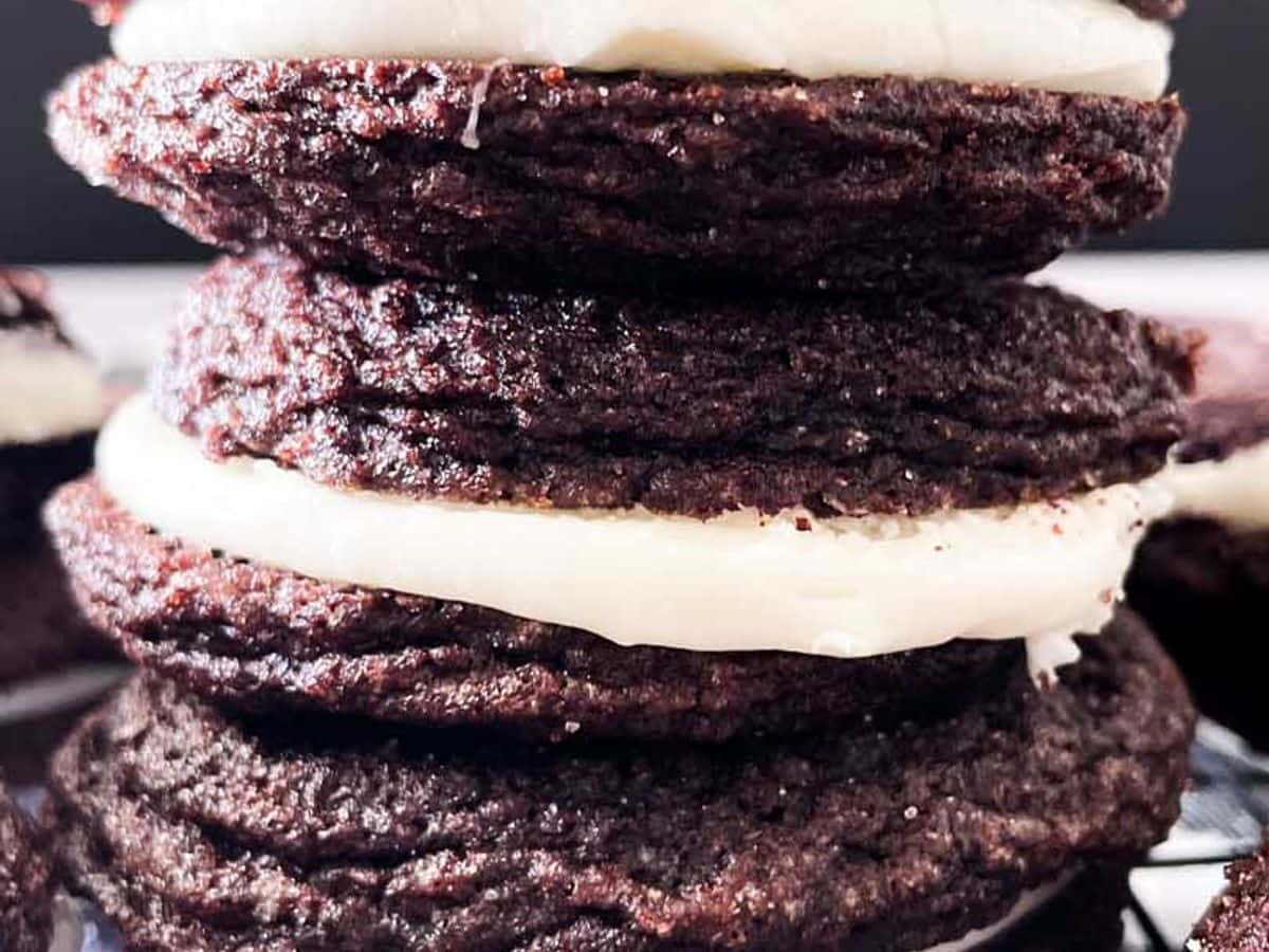 homemade oreo cookies with mascarpone filling stacked on top of each other on a cooling rack