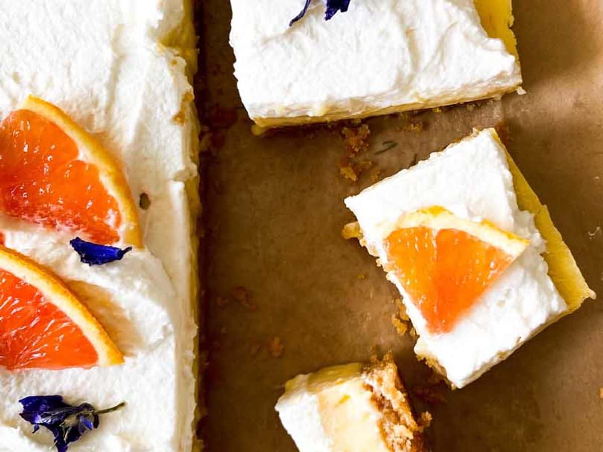 orange bars with honey whipped cream, topped with orange slices and cut into pieces ready to serve