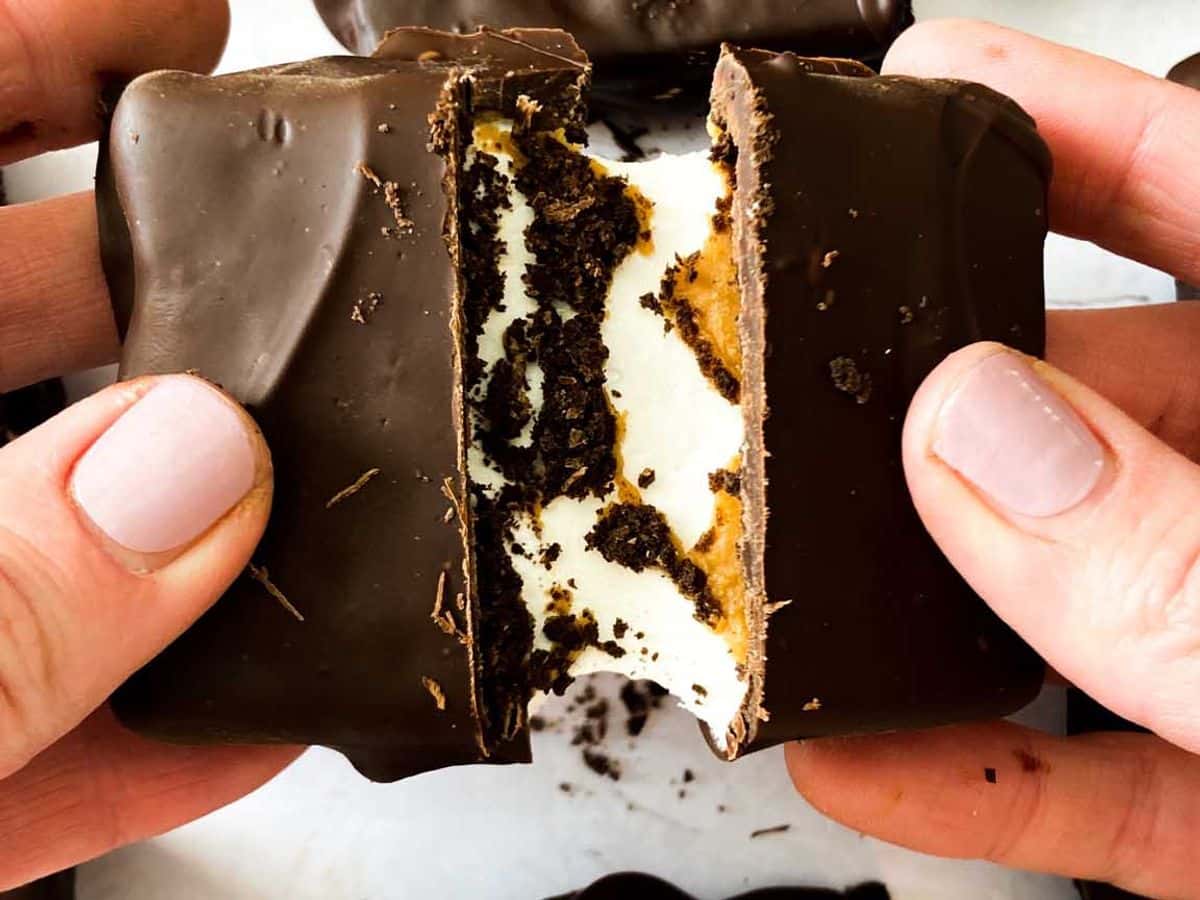 peanut butter smores bars being broken and pulled apart in hands to show gooey marshmallow filling