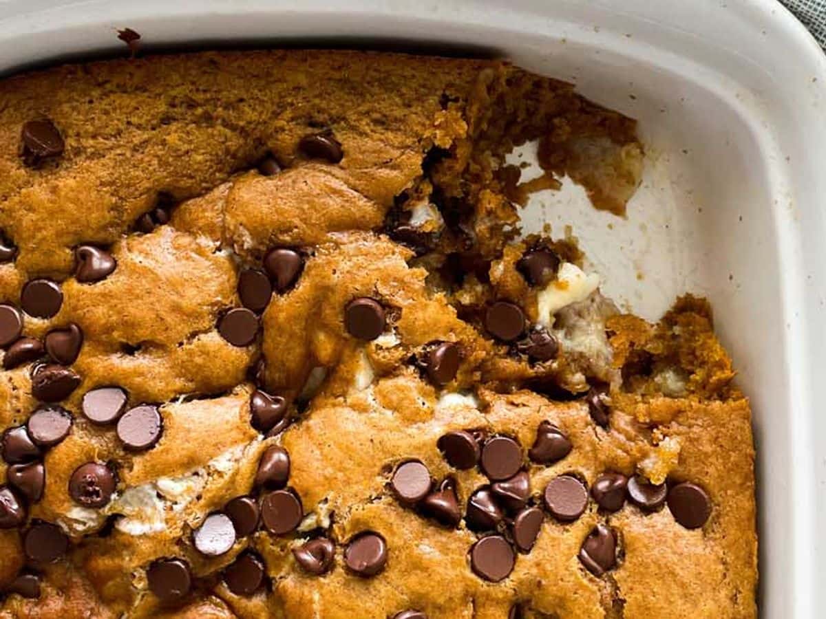 pumpkin cake with cream cheese filling and chocolate chips in dish with piece missing