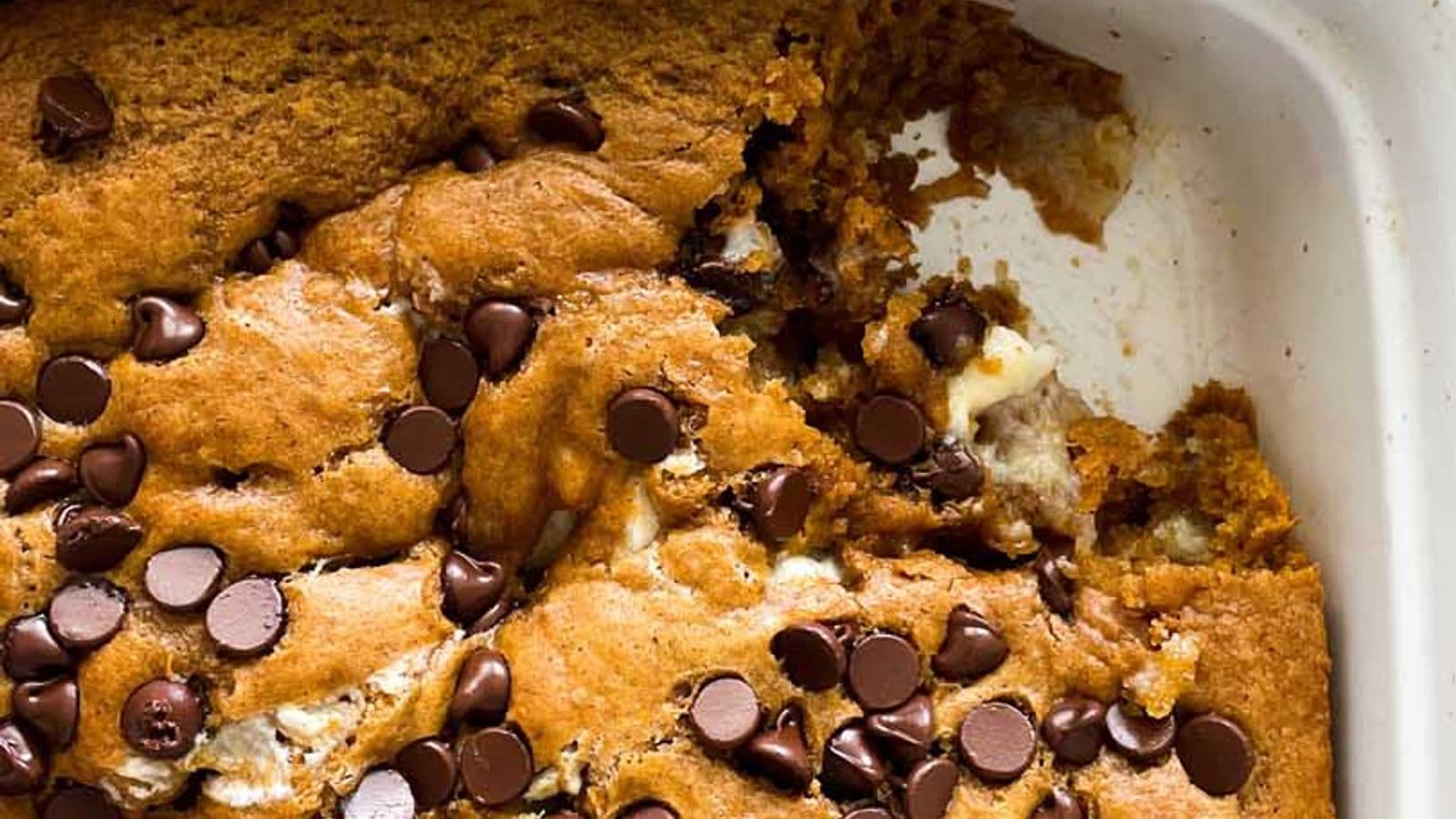pumpkin cake with cream cheese filling and chocolate chips in dish with piece missing