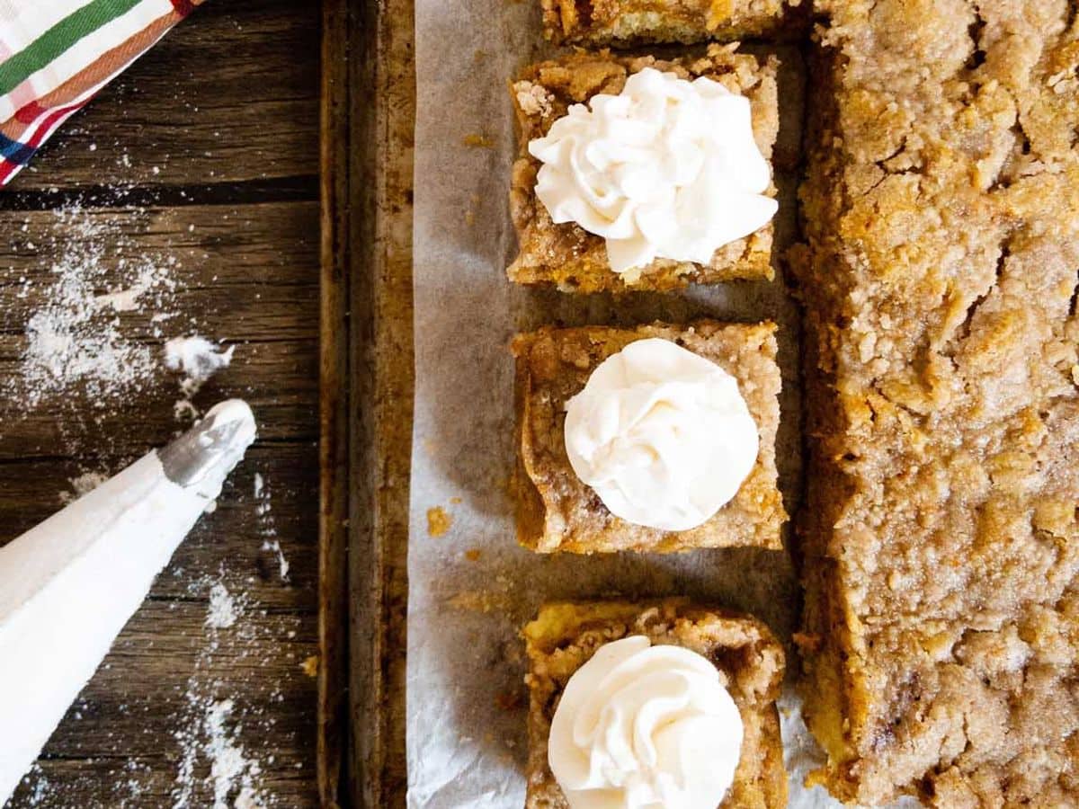 pumpkin pie cake with three pieces cut and topped with whipped cream