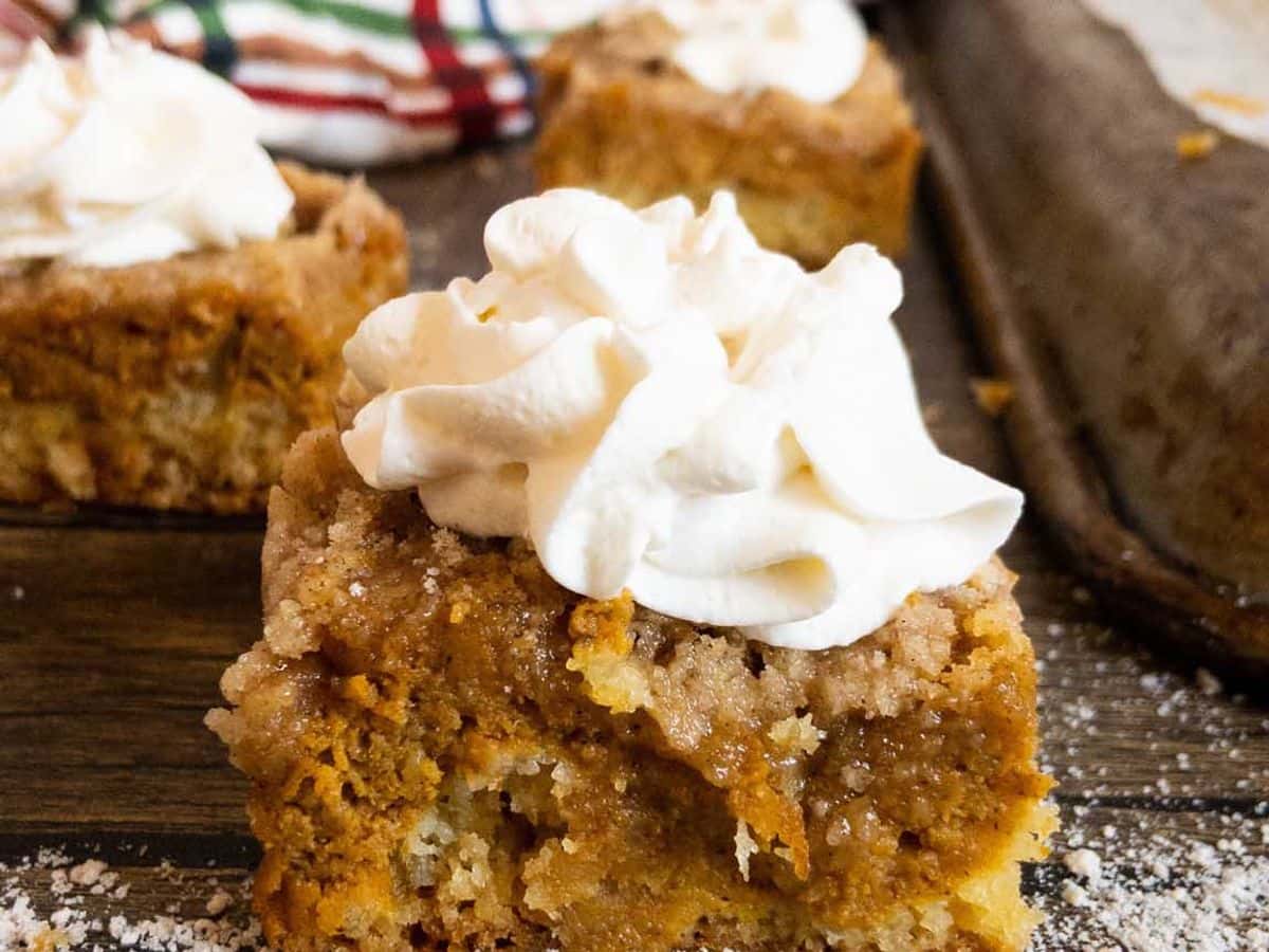 pumpkin pie cake piece topped with whipped cream and shown from the side to show the layers
