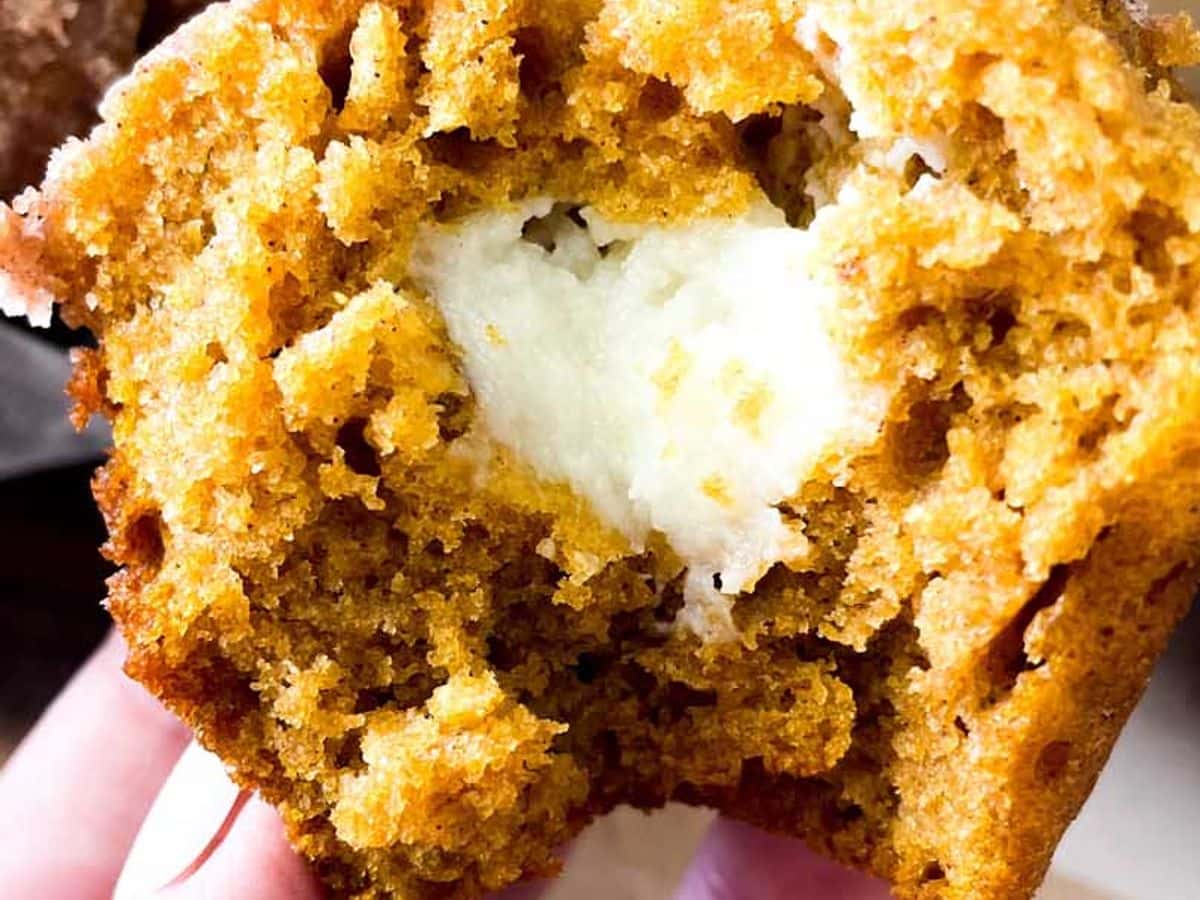 hand holding half of starbucks copycat pumpkin muffins showing cream cheese filling