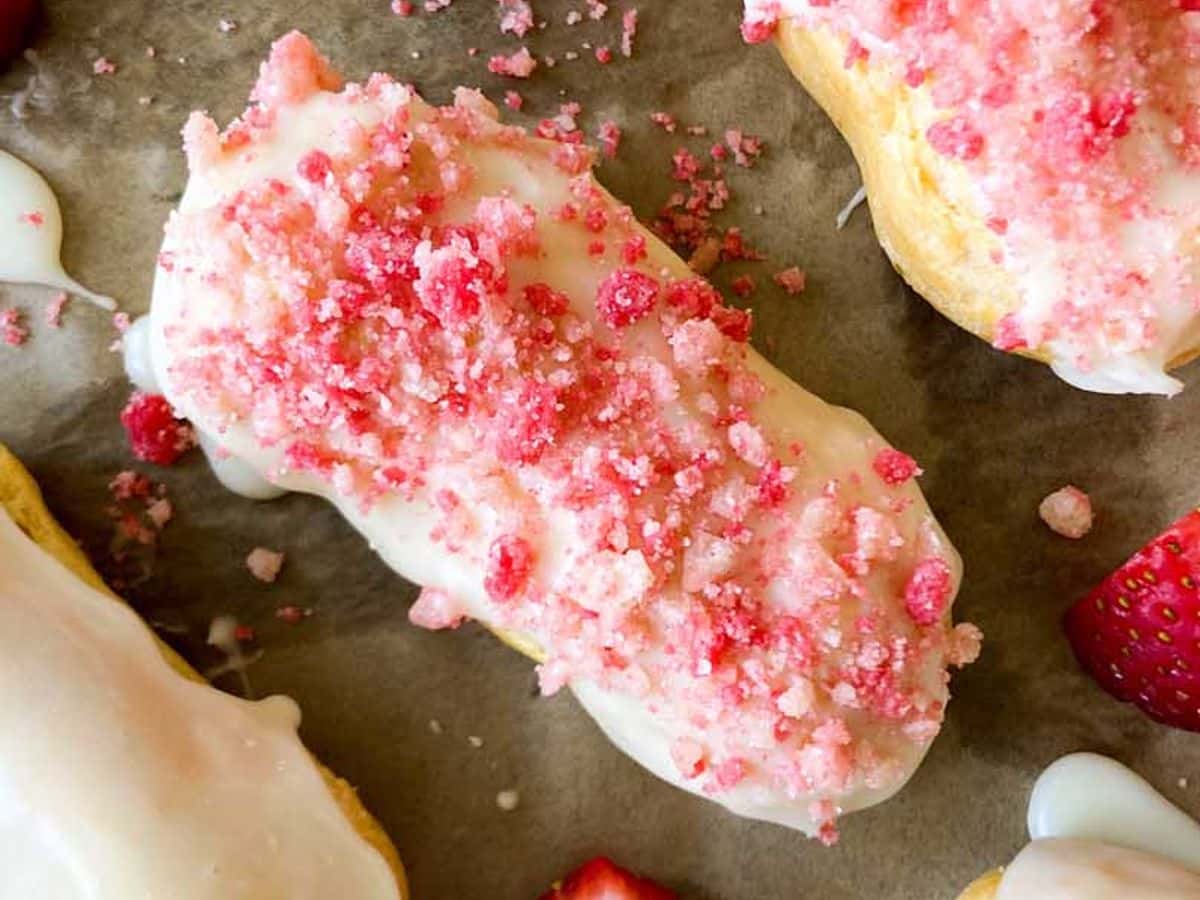 strawberry eclairs finished on baking sheet with strawberry crunch topping