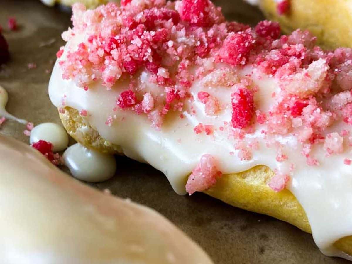 strawberry eclairs finished on baking sheet with glaze and strawberry crunch topping