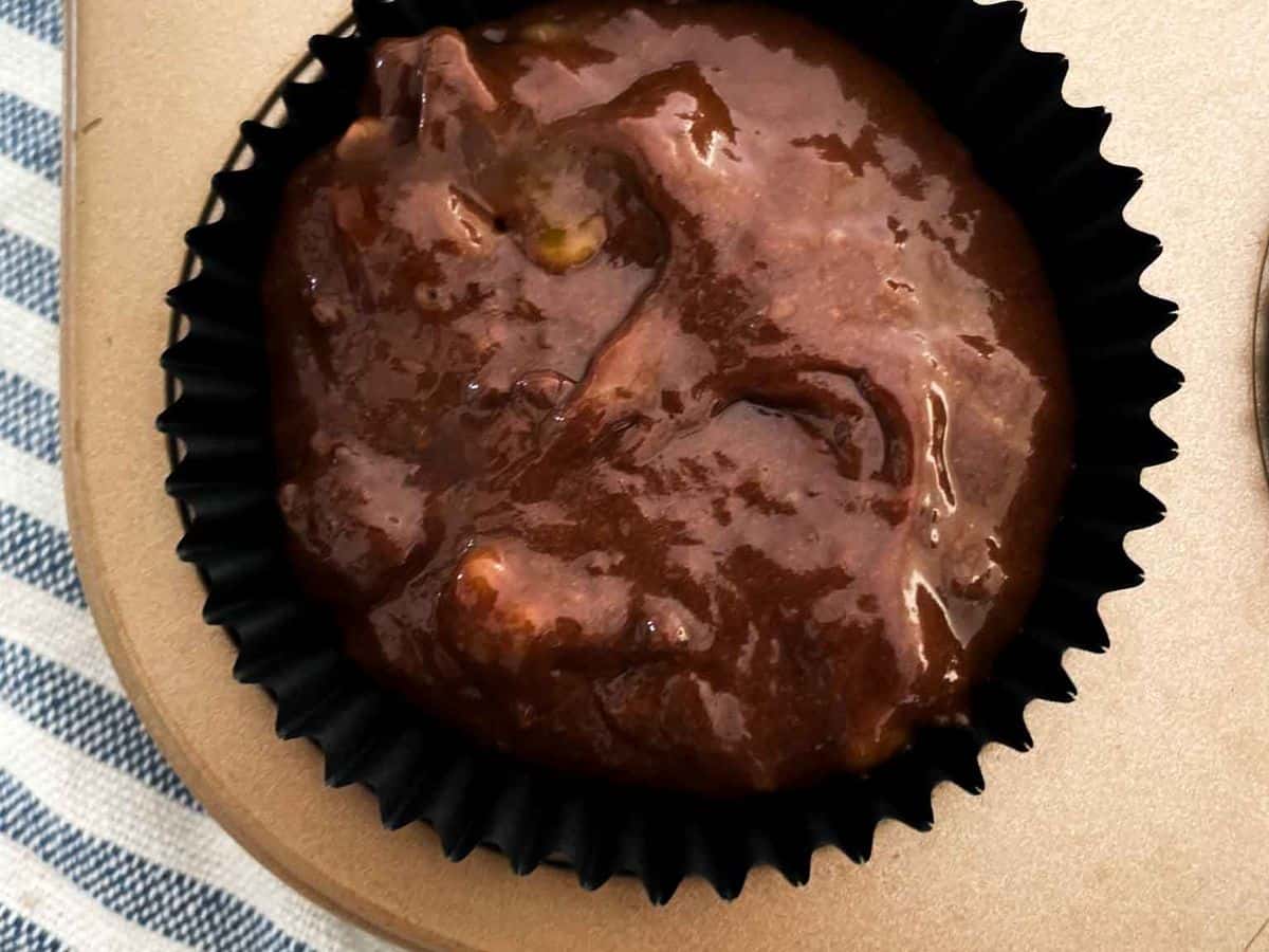 close up shot of the batter for the best chocolate chocolate chip banana muffins inside a gold muffin tin