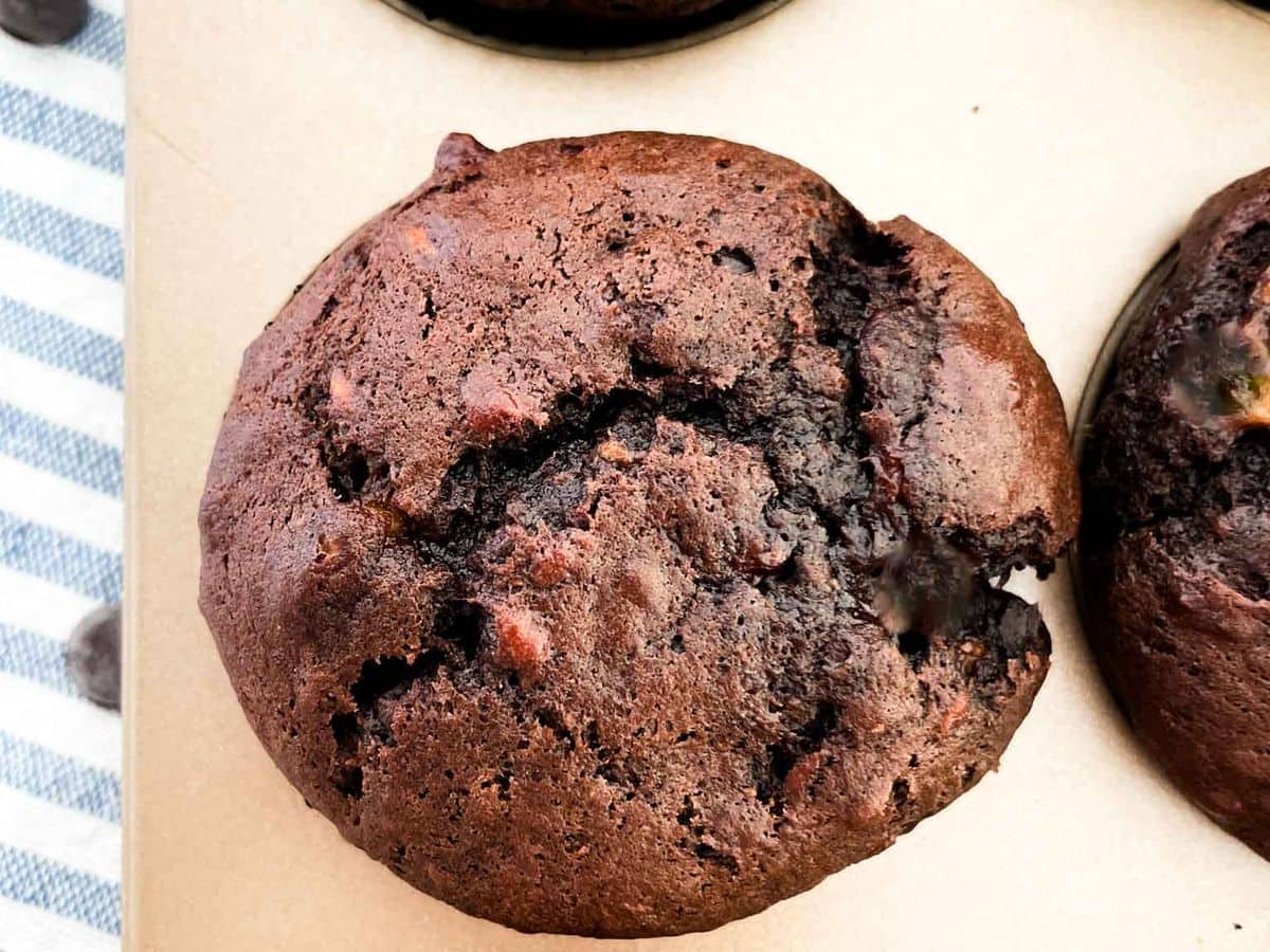 close up shot of the best chocolate chocolate chip banana muffins inside a gold muffin tin