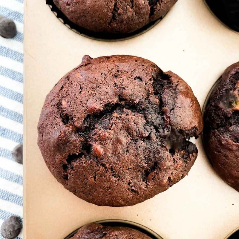 close up shot of the best chocolate chocolate chip banana muffins inside a gold muffin tin