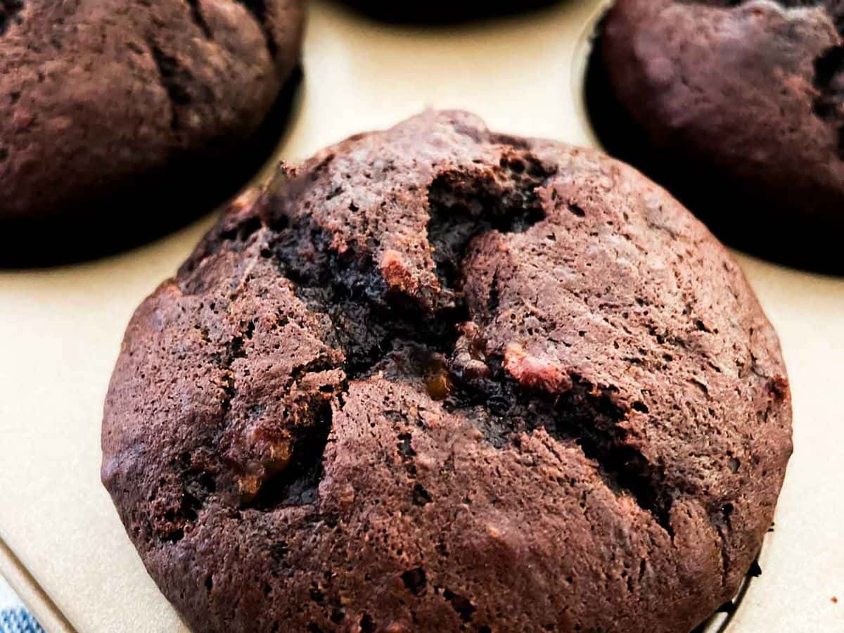 close up shot of the best chocolate chocolate chip banana muffins inside a gold muffin tin