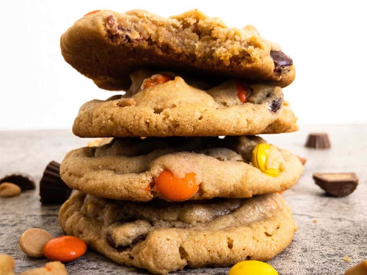 peanut butter cookies stacked on top of each other with Reese's pieces, mini Reese's cups, and peanut butter chips