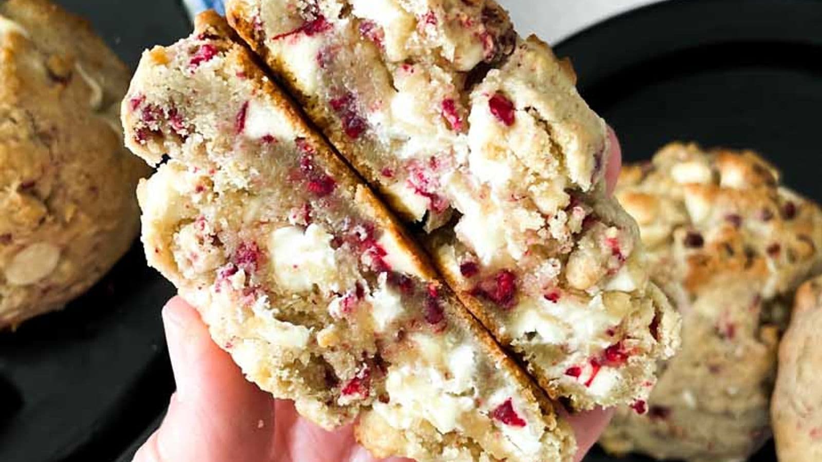 white chocolate raspberry cookie cut in half with both halves held in hand showing inside